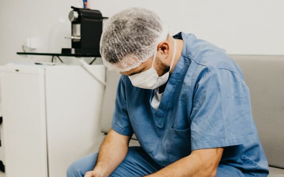 A man in hospital scrubs wit his head down