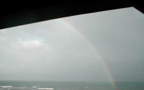 rainbow in grey clouds over sea