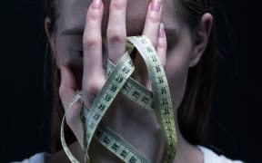 Anorexic girl covering her face with a centimeter