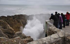 Tourists enjoy the main blowhole in action at the Pancake Rocks, Punakaiki