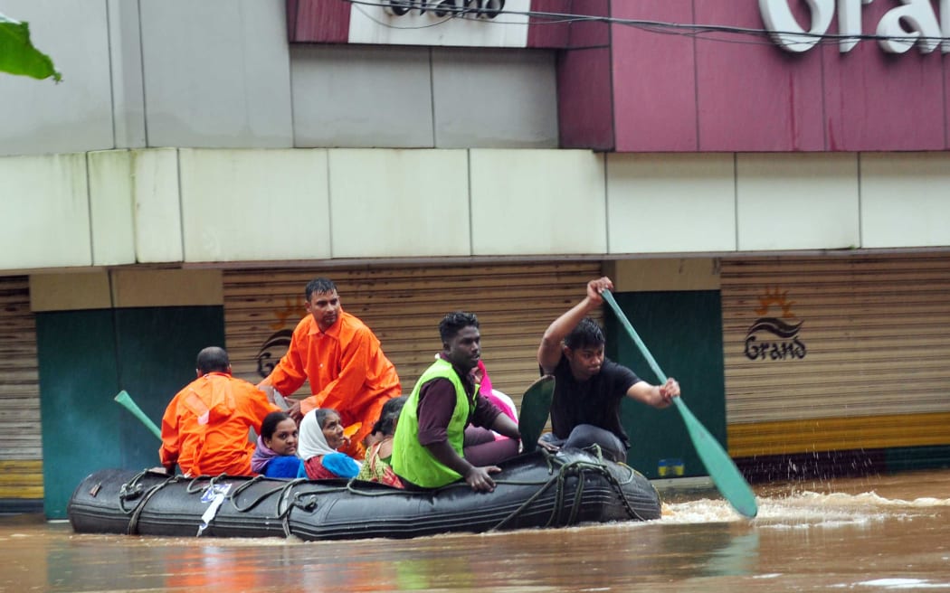 Indian navy and rescue personnel evacuate local residents in an boat at Aluva, in the Indian state of Kerala
