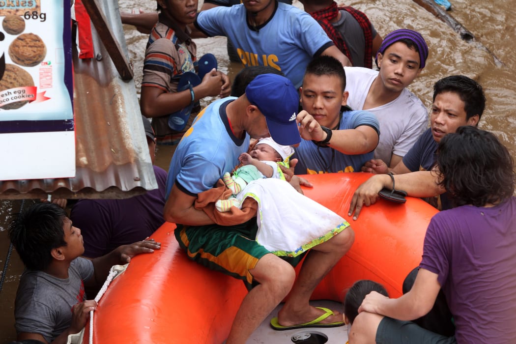 Policemen ecavuate a baby in Cagayan City on Friday 22 December 2017, after the Cagayan River swelled from heavy rains brought by Tropical Storm Tembin.