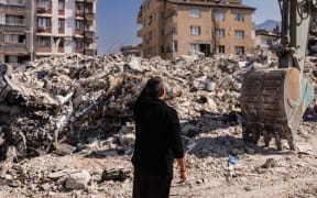 A man stands in front of collapsed buildings in Antakya, southern Turkey on 20 February 2023. The buildings were destroyed in the deadly 6 February 7.8 and  7.5-magnitude quakes.