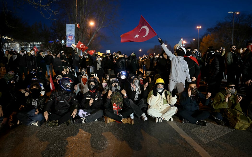 Protesters sit in front of Turkish riot police on 22 March, 2025, during a demonstration outside Istanbul's city hall to support Istanbul mayor Ekrem Imamoglu, following his arrest in connection with two probes.