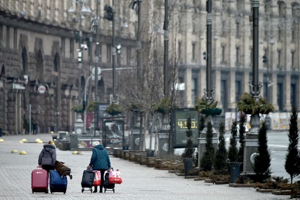 Women carry their belongings as they walk along a deserted street in the Ukrainian capital of Kyiv on 1 March, 2022.