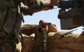 A Kurdish fighter uses binoculars on the front line in the northeastern Syrian city of Hasakeh. The US plans to send 250 more troops to encourage more people to join the Kurdish fighters.