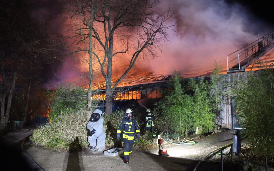 01 January 2020, North Rhine-Westphalia, Krefeld: Firefighters stand in front of the burning monkey house of the Krefeld Zoo.