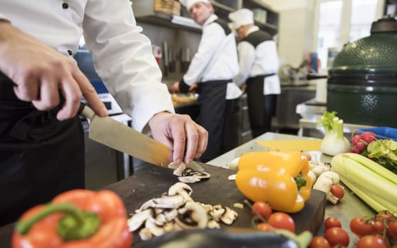 A group of people cooking in a commercial kitchen.