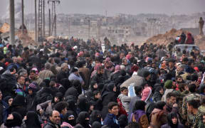 Syrian families, fleeing from various eastern districts of Aleppo, queue to get onto governmental buses on November 29, 2016 in the government-held eastern neighbourhood of Jabal Badro
