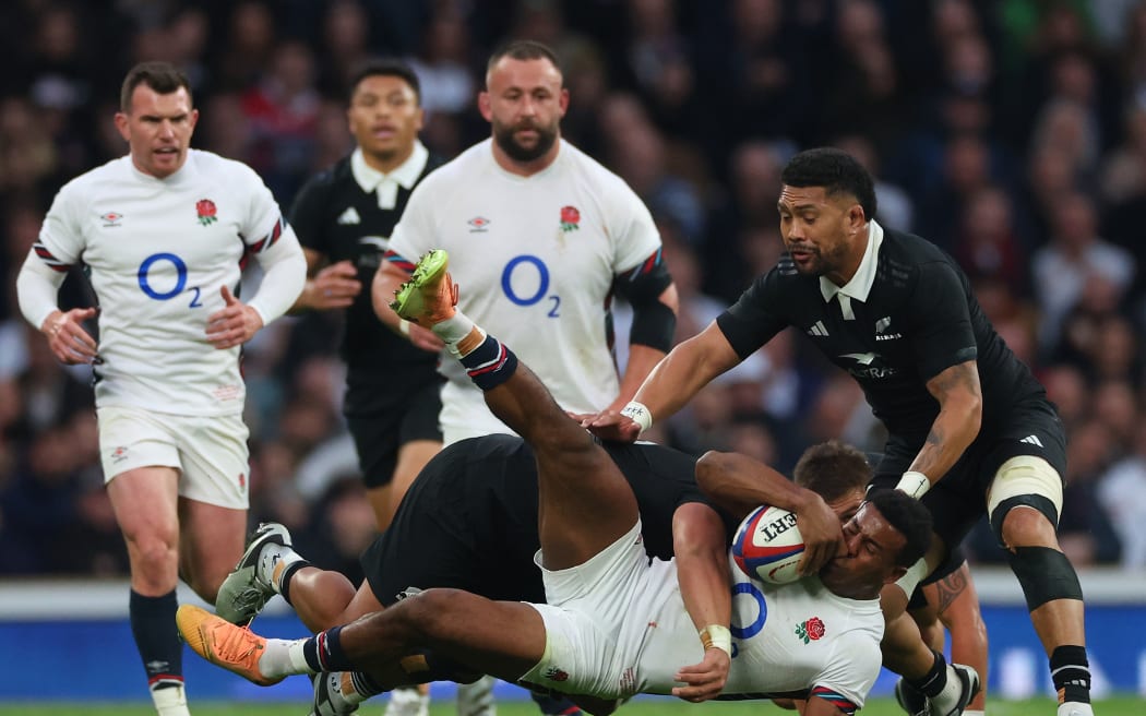 England's Immanuel Feyi-Waboso is tackled by All Blacks hooker Asafo Aumua as Ardie Savea watches on.