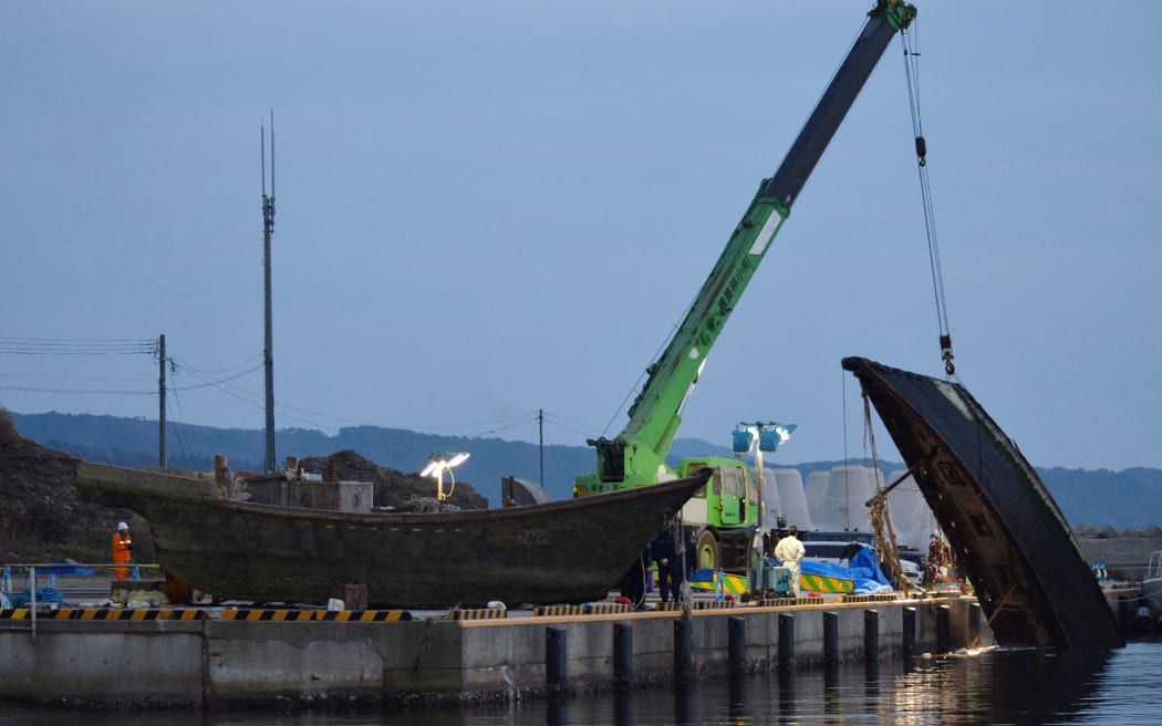 This picture taken on November 21, 2015 shows a wooden boat being salvaged at a port in Wajima in Ishikawa prefecture, central Japan. Mystery surrounds a fleet of ghost boats with headless skeletons or rotting corpses on board that are washing up on Japan's shores.