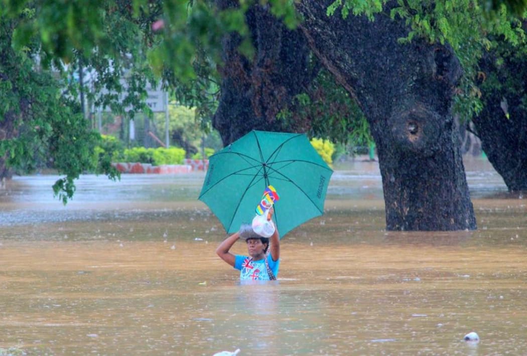 Residents of Korociri settlement cross through the flooded Nadi backroad in Fiji.