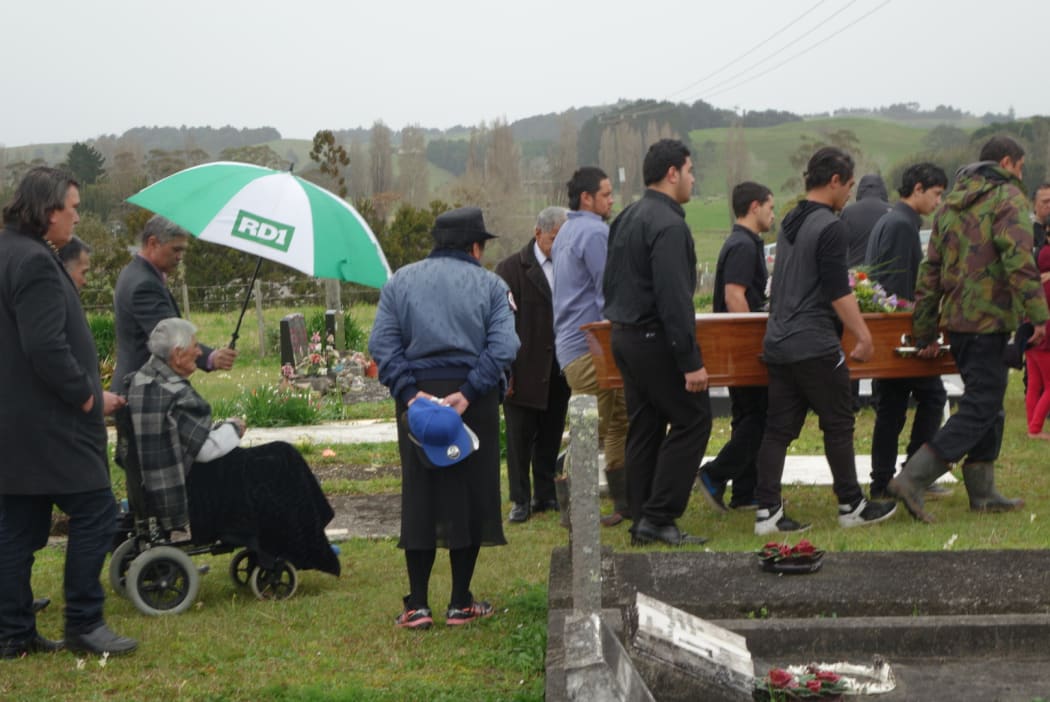 Mourners carry the coffin to the graveside.