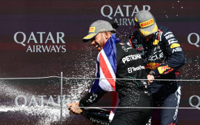 Lewis Hamilton, left, and Max Verstappen spray champagne after Hamilton's win in the 2024 British Grand Prix at Silverstone.