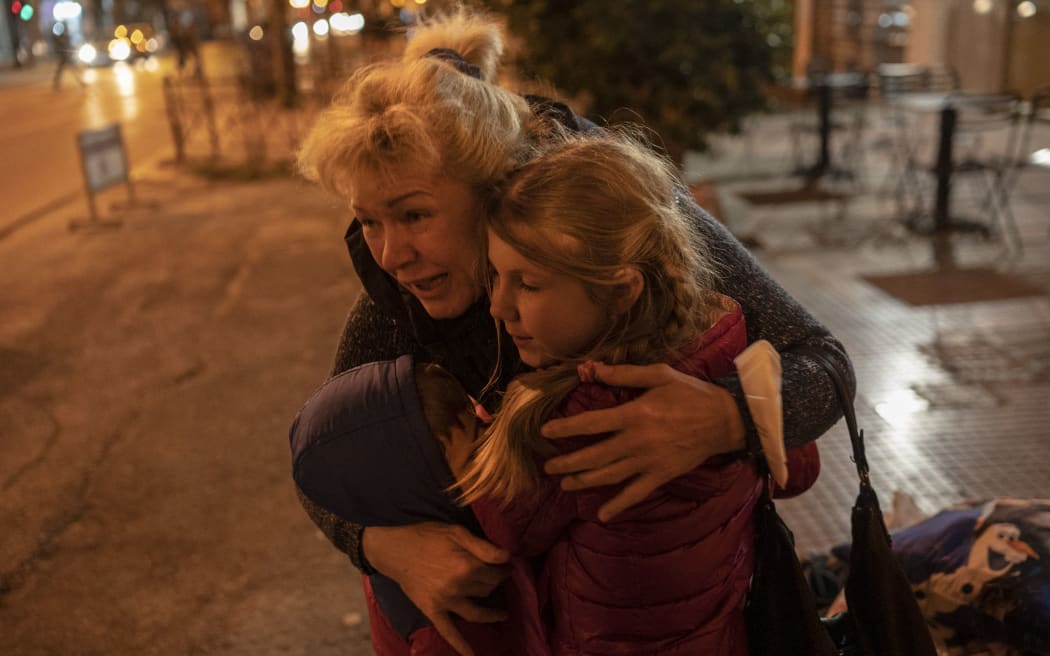 An Ukrainian refugee from from the Black Sea port city of Odessa, hugs two children as they arrive in Athens by bus, following the Russian invasion of Ukraine on March 6, 2022.