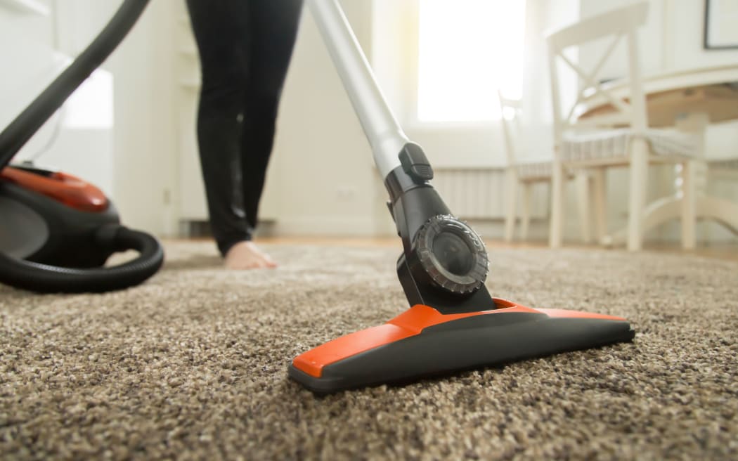 Close up of the vacuum cleaner, focus on the brush, woman cleaning the carpet. Home, housekeeping concept