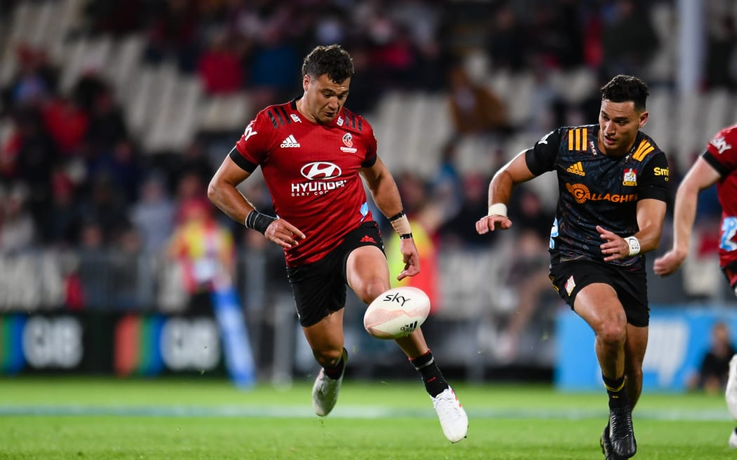 David Havili of the Crusaders (L) kicks the ball from Shaun Stevenson of the Chiefs.