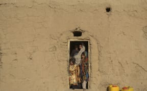 An Afghan family stands by the door of their home in the village Haji Rashid Khan in Badghis province where climate change is proving a deadlier foe than the country's recent conflicts.