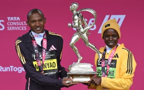 Winners of the men's and women's races, Kenya's Alexander Mutiso Munyao (L) and Kenya's Peres Jepchirchir (R) pose with the trophy at the presentations for the 2024 London Marathon in central London on April 21, 2024. (Photo by JUSTIN TALLIS / AFP) / “Restricted to editorial use - sponsorship of content subject to LMEL agreement”.