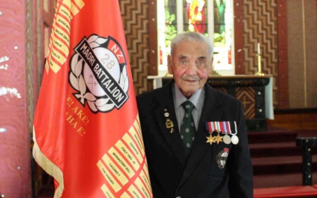 Tā Robert Gillies Kamupene B, 28 (Māori) Battalion stands with Aake Ake Kia Kaha, The 28 (Māori) Battalion 
Battle Honours Memorial Flag at St Faiths, Ohinemutu.