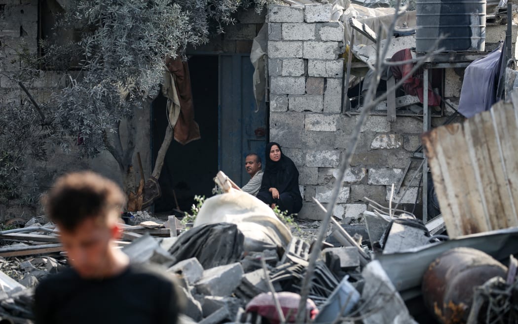 Palestinians sit amid the rubble of a house in the aftermath of an overnight Israeli strike that hit Nuseirat in the central Gaza Strip on 13 July 2025.