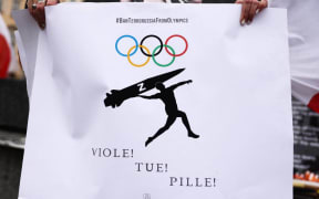 A woman shows a banner calling to ban Russian and Belarusian athletes from the Paris 2024 Summer Olympics while attending a demonstration of solidarity with Ukraine at the Main Square on day 404th of Russian invasion on Ukraine. Krakow, Poland on April 3rd, 2023. Nearly one year since the Russian attack, there is no end is in sight to the war in Ukraine.  (Photo by Beata Zawrzel/NurPhoto) (Photo by Beata Zawrzel / NurPhoto / NurPhoto via AFP)