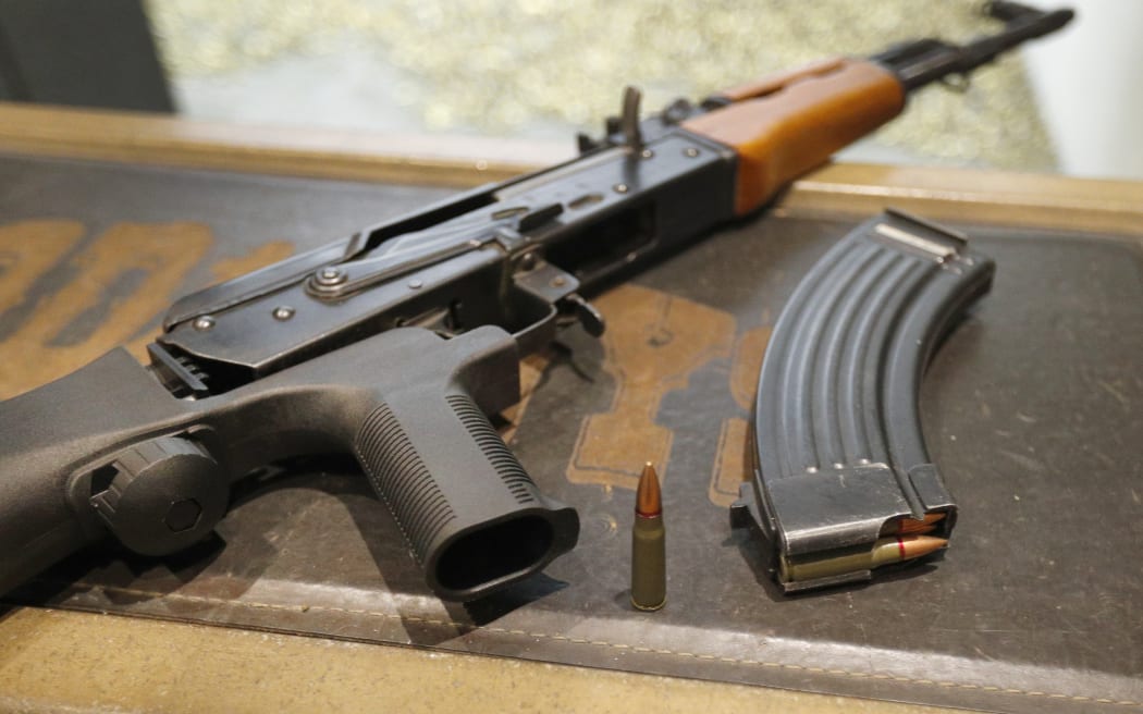 A 7,62X39mm round sits next a a 30 round magazine and an AK-47 with a bump stock installed.