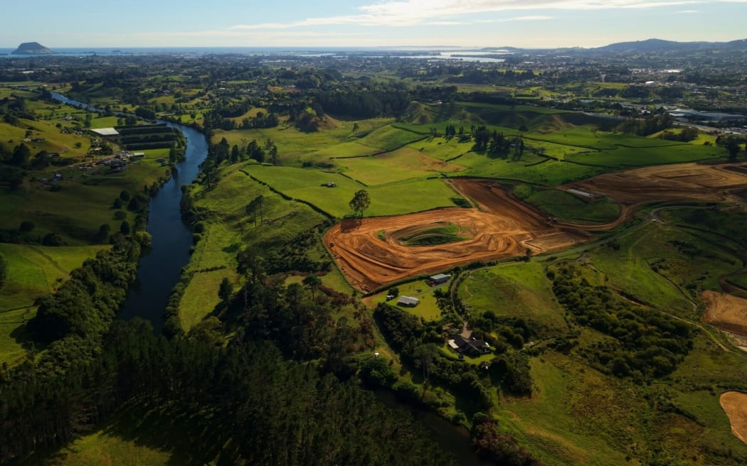 Aerial photo of green paddocks beside river and an area where earthworks have begun