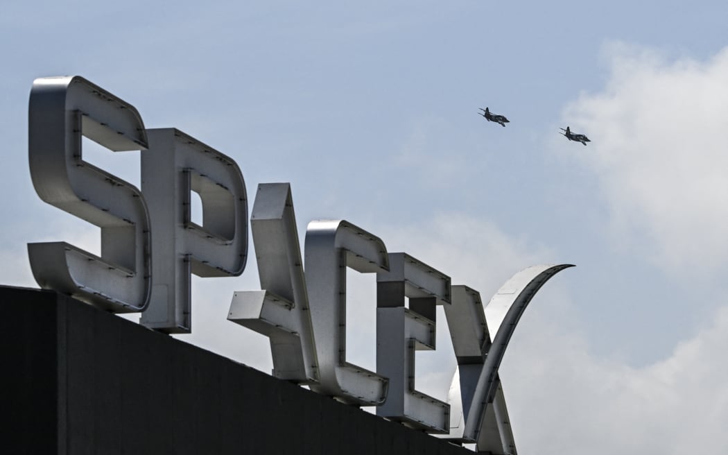 US billionaire businessman and pilot Jared Isaacman flies in formation aboard a fighter jet over the SpaceX sign, close to the Starship spacecraft, before his third test flight from Starbase in Boca Chica, Texas, on March 13, 2024.