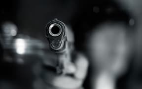 Black and white, woman pointing a old gun to front with one Hand on dark background