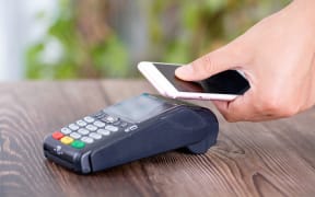 A mobile phone with a QR code is used to make a payment.