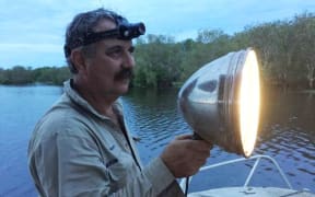 Crocodile catching contractor Roger Matthews looks for crocodile eye shine.