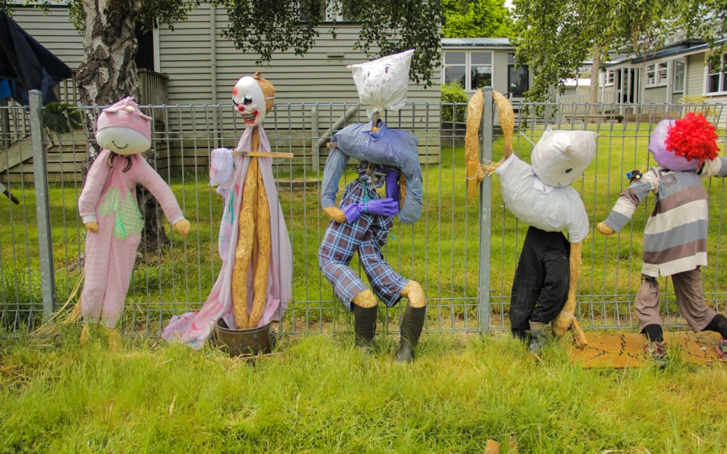 A school fence line covered in handmade scarecrows.