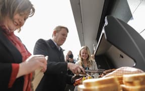 Chris Hipkins enjoys a sausage after helping out on the barbecue at Ara Ake in New Plymouth while on the election campaign trail on 25 September 2023.