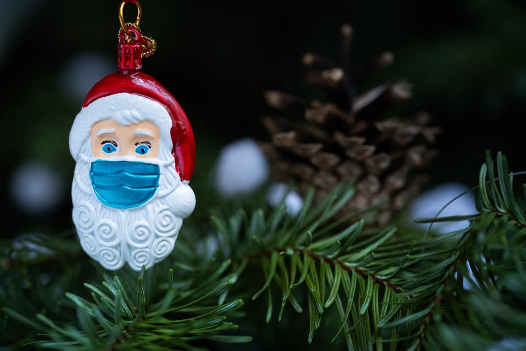 This picture taken in Paris on December 22, 2020 shows a Christmas Santa Claus decoration, with a protective mask. (Photo by JOEL SAGET / AFP)