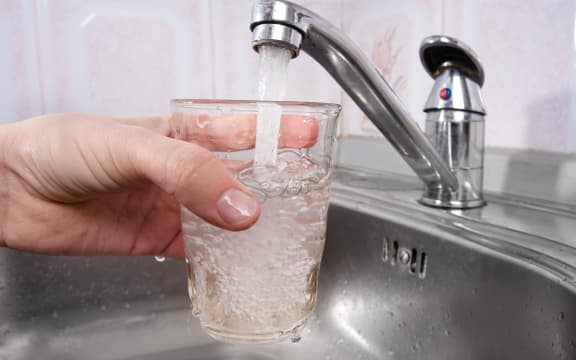 A glass is filled with drinking water from a tap