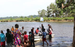 A group of villagers on the Carteret Islands wade into a bay to receive a supply boat.