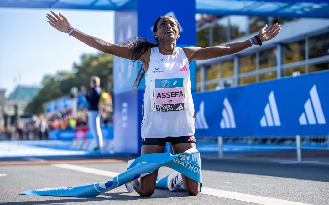 Tigst Assefa from Ethiopia kneels on the ground after winning the Berlin Marathon.