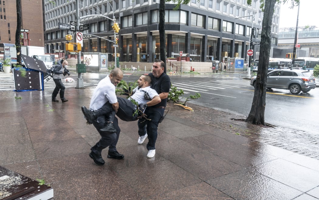 Co-workers carry injured maintenance worker by downed by strong wind tree after tropical storm Isaias lashes out New York City.