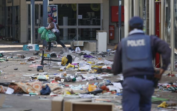 A looter runs from a member of the South African Police Services (SAPS) inside the Lotsoho Mall in Katlehong  township, East of Johannesburg, on July 12, 2021.