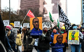 People hold placards as they protest outside of the Courthouse during the trial of former Minneapolis police officer charged with murdering George Floyd in Minneapolis, Minnesota on April 19, 2021.