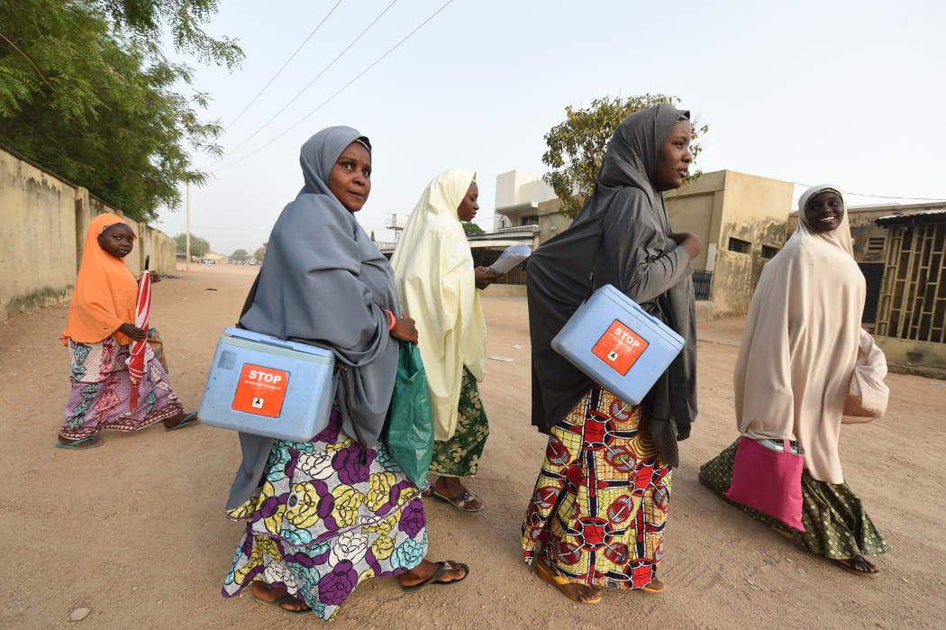 Health workers walk from house to house in search of children to immunise during a vaccination campaign in northwest Nigeria