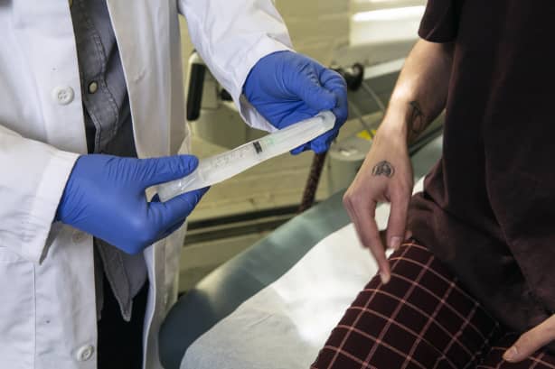 A doctor showing a patient a syringe used to inject testosterone. Guidelines:: https://genderspectrum.vice.com/guidelines