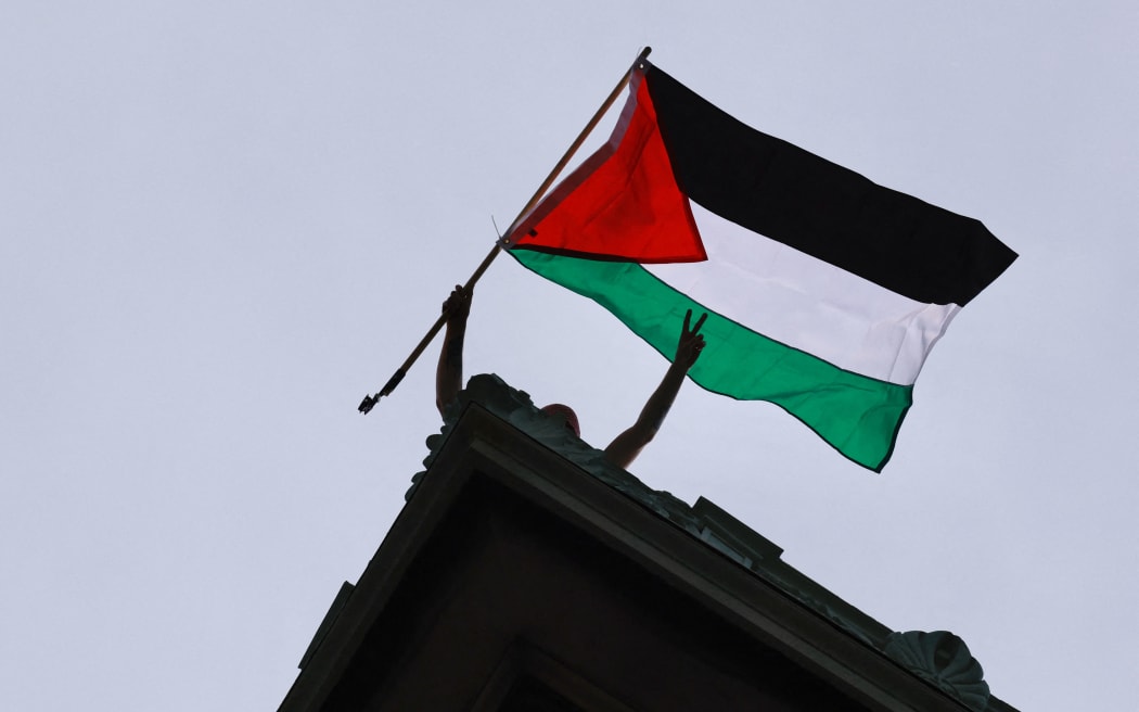 A person waves a Palestinian flag as Pro-Palestinian student protestors and activsits demonstrate outside of Columbia University in New York on April 30, 2024. Demonstrators at Columbia University barricaded themselves inside a campus building early Tuesday, escalating a standoff with school officials as pro-Palestinian protests upend campuses across the United States. (Photo by Kena Betancur / AFP)