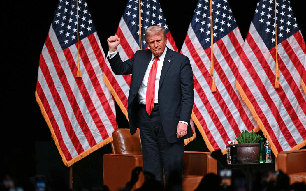 Former US President and Republican presidential candidate Donald Trump pumps his fist at the end of a live interview with US commentator Tucker Carlson in the finale of the Tucker Carlson Live Tour at Desert Diamond Arena in Glendale, Arizona, on October 31, 2024. (Photo by Patrick T. Fallon / AFP)