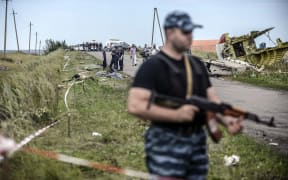 Armed pro-Russian separatists stand guard in front of the Malaysia Airlines crash site.