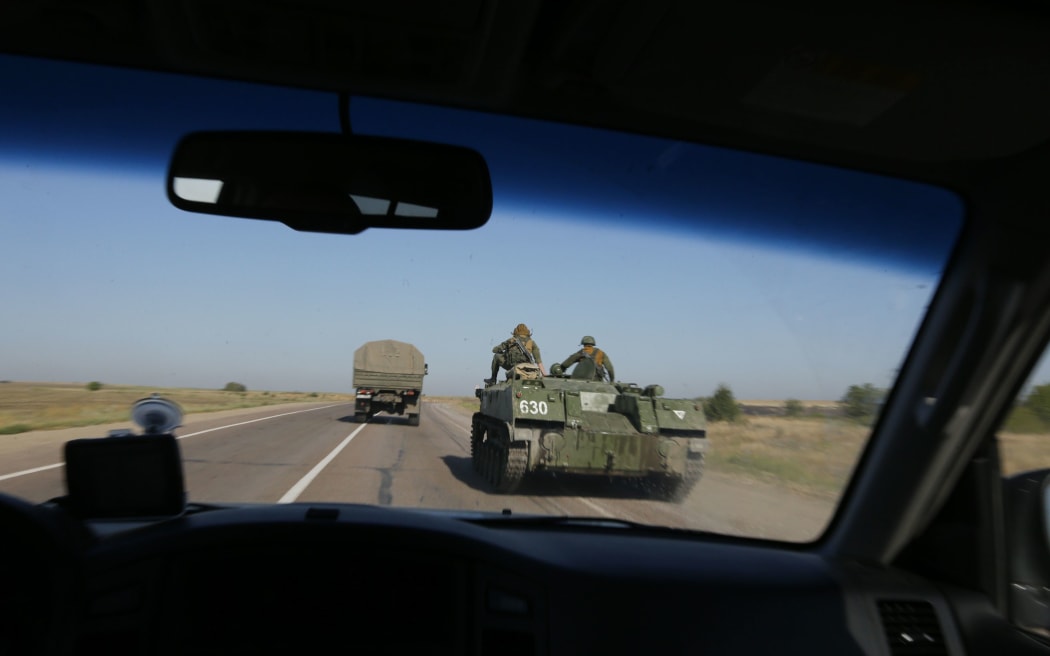 Russian servicemen are seen through a car window as they drive a military vehicle along a road near the border with Ukraine.