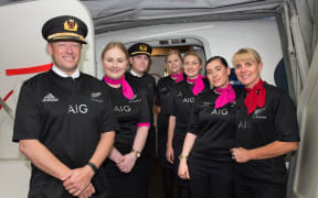 The crew on the Sydney-to-Auckland flight wearing All Blacks gear after Australia lost to New Zealand in the RWC 2015 final.