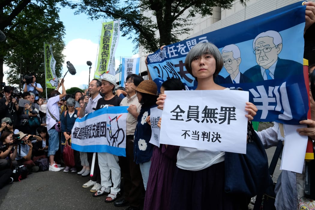 Activists hold placards in reaction during a rally in front of the Tokyo District Court in Tokyo after the court acquitted three former officials from the firm that operated the Fukushima nuclear plant.