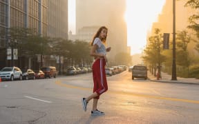 woman-wearing-white-t-shirt-and-red-track-pants-standing-in-the-middle-of-black-concrete-road